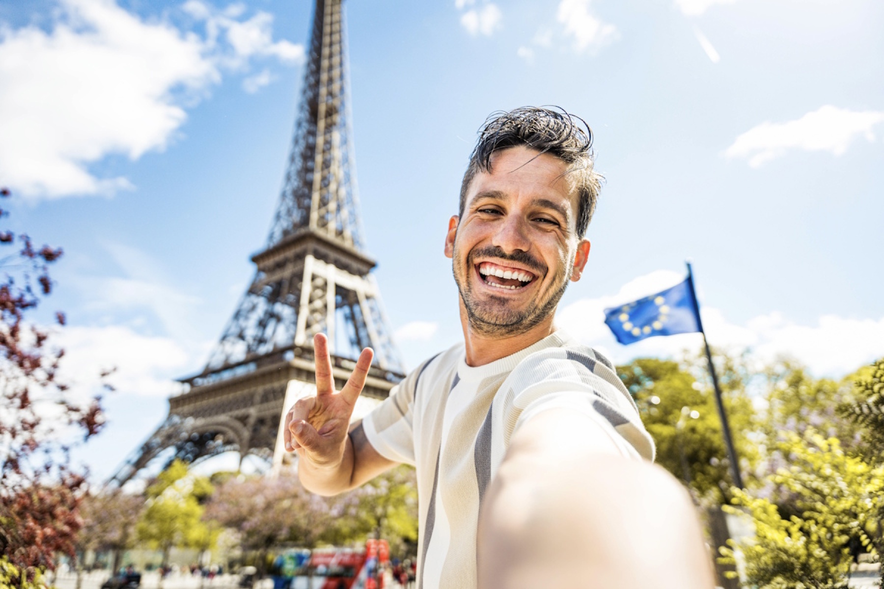 Illustration - Jeune homme heureux en stage d'anglais devant la tour Eiffel