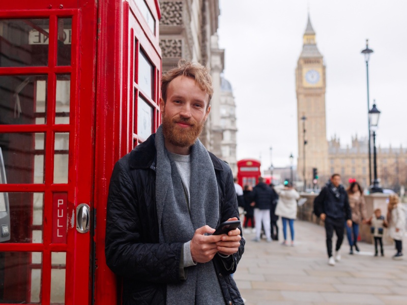 Homme élégant adossé à une cabine téléphonique à Londres