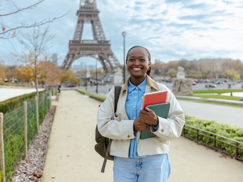 Jeune étudiante étrangère souriante devant la tour Eiffel